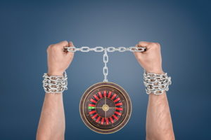 hands in chains tied to a roulette wheel