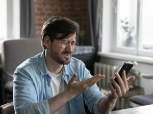 man frustrated looking at phone betting suspension